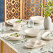 A table set with white Acopa Highlands dishes and a saucer next to a white cup.