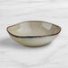 An Acopa Highlands heather gray china bowl with a blue rim on a marble surface.