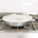 A Vollrath Wear-Ever aluminum non-stick fry pan with a black handle cooking on a stove.