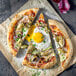 A pizza with vegetables and eggs including Yo Egg plant-based sunny side up egg on a white background.