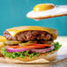 A burger with a Yo Egg plant-based sunny side up egg, lettuce, and tomato.