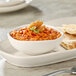 An Acopa Birch white china sauce cup filled with red sauce on a table with flat bread.