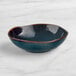 An Acopa Highlands skyfall blue china bowl with a brown rim on a marble surface.