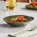 An Acopa Highlands juniper green china bowl filled with salad on a table.