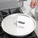 A person using a Vollrath Wear-Ever aluminum non-stick fry pan with a chrome plated handle on a stove.