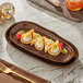 A rectangular brown Acopa Highlands china tray with food on a table.