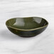 An Acopa Highlands juniper green bowl on a marble surface.