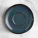 A blue Acopa Highlands saucer with a clear circle on a marble surface.