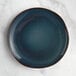An Acopa Highlands skyfall blue coupe china plate on a marble surface.