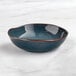 An Acopa Highlands blue china bowl with a brown rim on a marble surface.