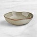 An Acopa Highlands heather gray china bowl with a brown edge on a marble surface.