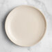 An Acopa Highlands white coupe china plate on a marble surface.