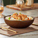 An Acopa Highlands round bowl filled with food on a table with a fork and knife.