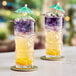 Two glasses of colorful Tiki Energy drinks with umbrellas on top.