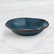 An Acopa Highlands Skyfall Blue China bowl with a brown rim on a marble surface.