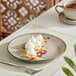 A Acopa Highlands heather gray coupe china plate with dessert and a cup of tea on a table.