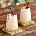 Two glasses of Tiki Breeze White Energy Drink with lime and rosemary on a wooden surface.