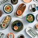 A table with Acopa Highlands rectangular white coupe trays holding plates and bowls of food.