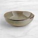 An Acopa Highlands china bowl with a speckled surface and a brown rim.