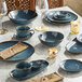 A table set with blue Acopa Highlands saucers and glasses.