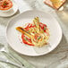 An Acopa Highlands white china plate with food on it on a table.