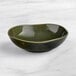 An Acopa Highlands juniper green china bowl on a marble surface.