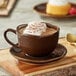 An Acopa Highlands china cup of hot chocolate with whipped cream on top on a table in a coffee shop.