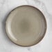 An Acopa Highlands heather gray coupe china plate on a marble surface.