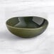 An Acopa Highlands juniper green china bowl on a marble surface.