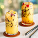 Two glasses of yellow passion fruit juice with black boba and metal straws.
