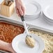 A person using a Thunder Group stainless steel basting spoon to serve rice and beans.