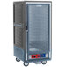 A large grey Metro holding and proofing cabinet with a clear door on wheels.