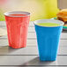 Two Solo Squared plastic cups on a table with burgers and drinks.