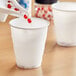 A hand pouring liquid into a Solo white plastic refill cup.