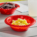 A red Solo plastic bowl filled with chips on a table.