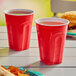 Two Solo Squared red plastic cups with liquid on a table.