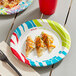A Solo AnyDay paper plate with food on it and a drink on a table.