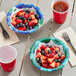 A table with Solo sea glass paper bowls filled with blueberries and strawberries and a cup of water.