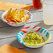 A Solo AnyDay paper bowl filled with guacamole on a table with a bowl of potato chips.
