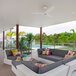 A patio with a white couch and a yellow pillow in the middle of a modern outdoor living area.
