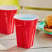 Two Solo red plastic cups with blue liquid on a table with a burger.