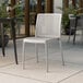 A white plastic Lancaster Table & Seating Rio side chair on an outdoor patio.