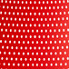 A white background with a red and white polka dot patterned tablecloth on a red Lancaster Table & Seating Rio Buoy resin arm chair.