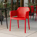 A red resin arm chair on a tile patio.