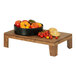 A Cal-Mil walnut display stand with a bowl of tomatoes and bread on a wood table.