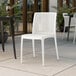 A Lancaster Table & Seating Rio Cloud White resin side chair on a tile floor.