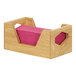 A Cal-Mil oak napkin holder on a table with pink napkins inside.