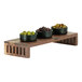 A Cal-Mil Sydney walnut display stand holding bowls of green and black olives.