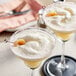 Two martini glasses filled with lychee drinks on a table.