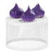 A group of purple garlic bulbs displayed on a white round stand with perforated metal.